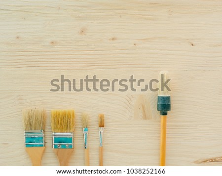 Paint brush and other painting supplies on white wooden planks, top view