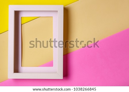 Minimalism style. White empty picture frame against  abstract colored paper background, with cope space, flat lay.