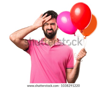 Handsome young man with fever holding balloons over isolated white background