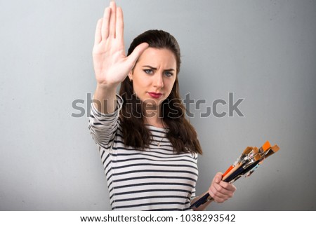 Young artist woman making stop sign on grey background