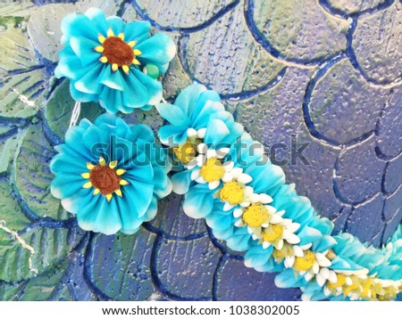 Colorful thai garland on the foam carved multicolored feathers wall.