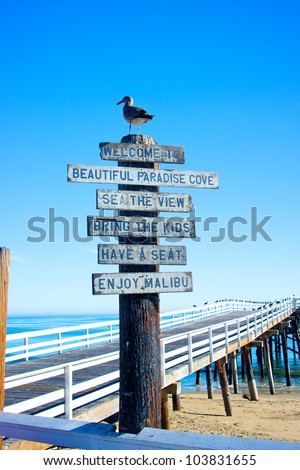A sign and a seagull welcome visitors to the pier at Malibu Beach in California.
