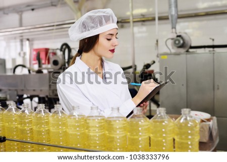 line of food production of refined sunflower oil. Girl worker at a factory on a conveyor background with bottles of vegetable oil.