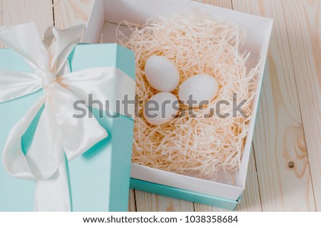 Three eggs are in a beautiful open box with a white bow. Organic farm products. The celebration of Easter.