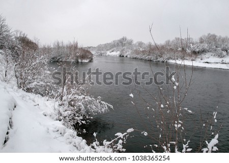 Beautiful winter scene on river after heavy snowfall. Branches of trees and shrubs loaded with snow after heavy snowfall.