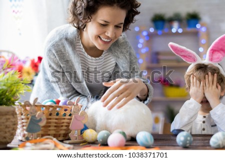 Portrait of happy mother and little boy  wearing bunny ears playing with bunny  at home celebrating Easter