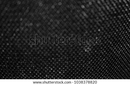 Blurry photo of black material grating with round bokeh for use as a background.