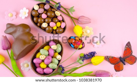 Happy Easter overhead with chocolate Easter eggs and decorations on a wood table background with copy space.