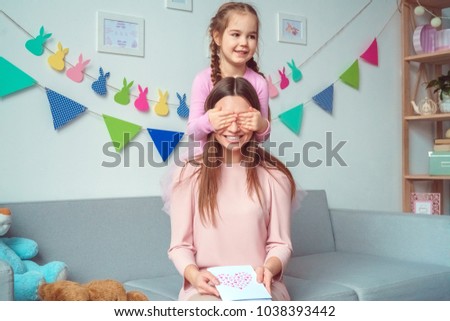 Mother and daughter together weekend at home on sofa girl making surprise to mom