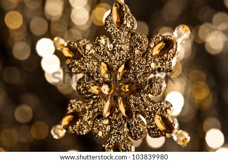 Artificial Snowflake in gold shining over a golden background