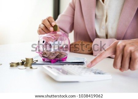 Close up of Businessman putting coin into small piggy bank , The concept of saving money and investment.