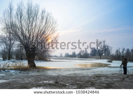 landscape photographer takes photos on frozen river floding area