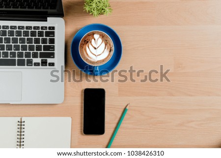 Modern office desk table with laptop computer,leather notebook,pen,smart phone and cup of coffee.Top view with copy space.Working desk table concept.