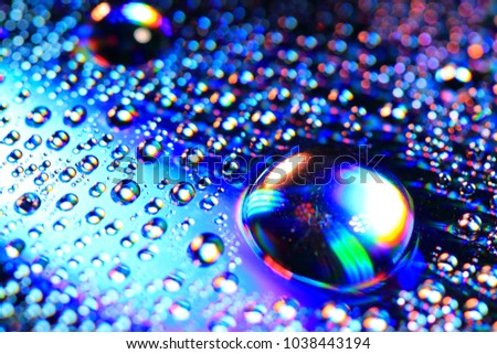 A macro photograph of water droplets on iridescent background with prismatic light and rainbow gradients. It almost looks like computer generated CG graphics. 