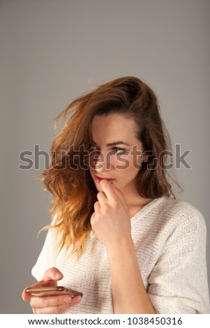 brunette girl thinking with on finger on her lips about a message on her smartphone