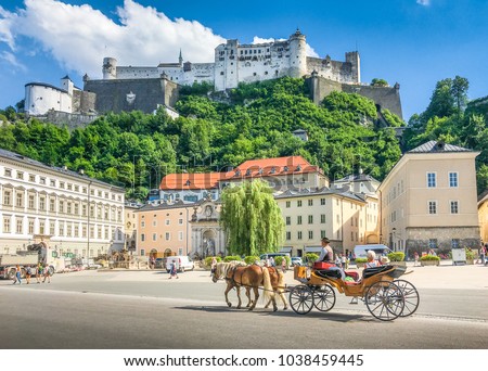 Beautiful panoramic view of the historic city of Salzburg with traditonal horse-drawn Fiaker carriage and famous Hohensalzburg Fortress on a hill on a sunny day with blue sky and clouds in summer Royalty-Free Stock Photo #1038459445