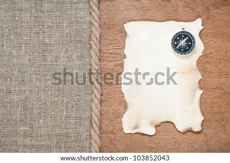 Compass on the old wood and canvas with rope background