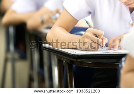 soft focus.high school or university student holding pencil writing on paper answer sheet.sitting on lecture chair taking final exam attending in examination room or classroom.student in uniform Royalty-Free Stock Photo #1038521200