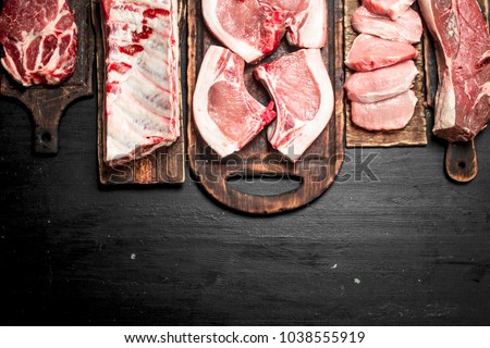 Different types of raw pork meat and beef. On the black chalkboard. Royalty-Free Stock Photo #1038555919