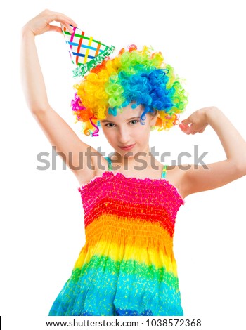 Charming little girl in multicolored clown wig and birthday party hat isolated on white background