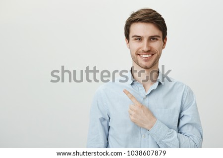 Portrait of handsome mature caucasian male entrepreneur pointing left with index finger while looking with confident bright smile at camera, being assured in his company successful deals Royalty-Free Stock Photo #1038607879