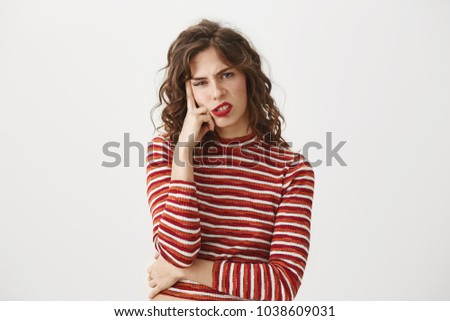 I am sick of you. Indoor shot of bored and disgusted attractive young woman leaning on finger and looking with disrespect or boredom at camera, standing over gray background. Royalty-Free Stock Photo #1038609031