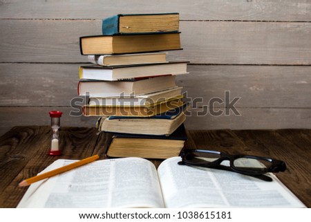 pile of books and hourglass glasses and pencil