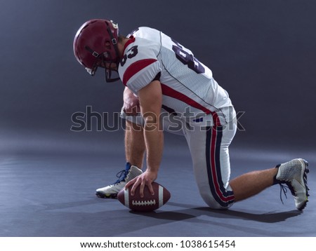 American football player getting ready before starting the game while standing against gray background