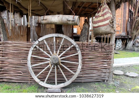 Old cart wheel with vintage background. Vintage wooden wheel near old fence. Retro style.