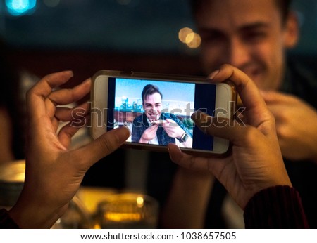Young adult couple on a dinner date taking smartphone photos