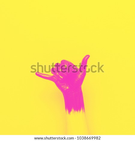surf Shaka gesture by black painted hand on pink background. minimal style of summer. yellow and pink double color effect 