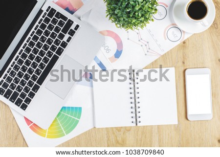 Top view of modern wooden office desk with empty notepad, electronic device, other supplies and coffee cup. Lifestyle, project and occupation concept. Mock up 