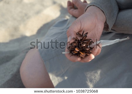 Woman holds a fir cone and bird feather in her hand