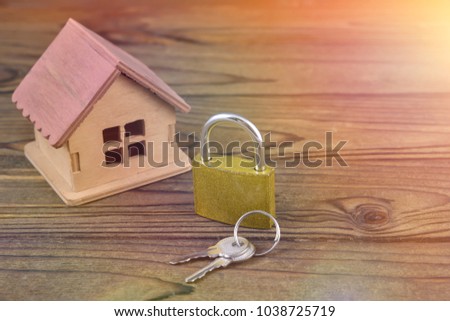 Concept of a small house and a golden lock with keys. on a natural wooden background. The idea: security, protection, alarm, law and order.