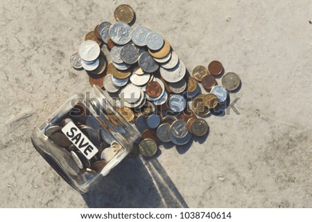 Coins mix fall out of glass jar with label save on floor, copy space. Saving money, economic crisis and financial stability concept