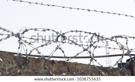 Concrete fence with barbed wire on the background of blue sky.