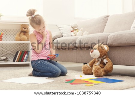 Happy little girl drawing. Cute kid sitting at home on the floor among cologed paper and pencils. DIY, creative art hobby, early development and inspiration concept