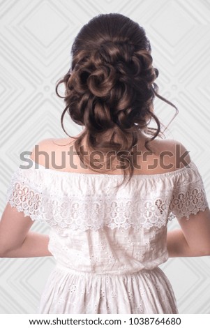 Young sweet brunette with beautiful hairstyle posing in studio