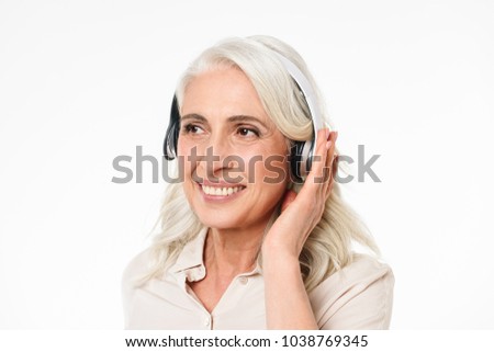 Close up portrait of a happy mature woman listening to music with headphones isolated over white background