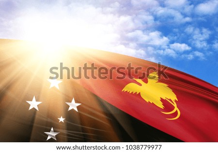 flag of Papua New Guinea against the blue sky with sun rays