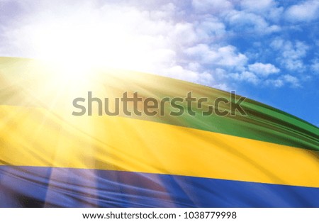 flag of Gabon against the blue sky with sun rays