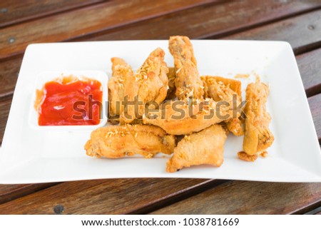 Fried chicken wings with sauce on white dish.