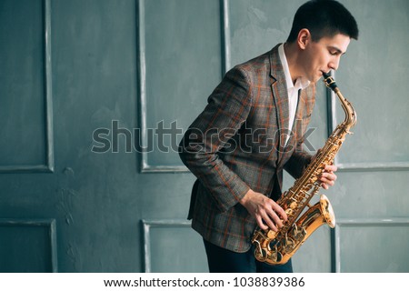 Male saxophonist plays jazz saxophone in the room