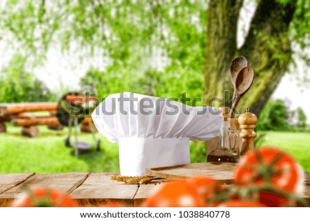 Cook hat on wooden table with free space for your decoration and grill background in garden. Spring time. 
