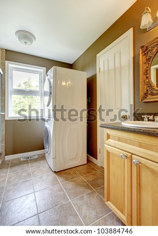 Laundry room with bathroom cabinet and sink and ceramic tiles.