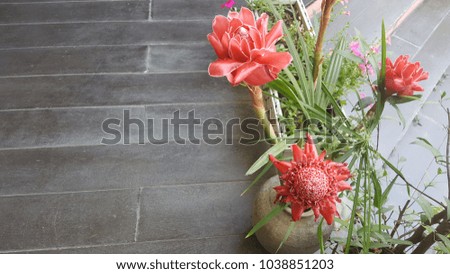 Flowers in a vase are placed on the floor.