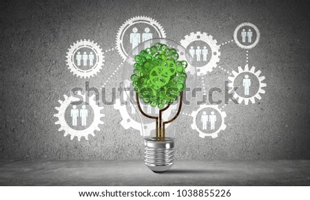 Lightbulb with tree from gears inside placed against social gear structure sketched on grey wall. 3D rendering.