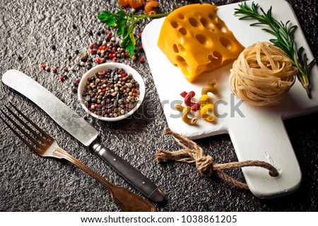 Pasta in a composition with vegetables and kitchen accessories on an old background
