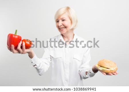 A picture of dilemma between good and bad meal. What is better to choose: two good peppers or one tasty burger .The answer is obvious but not easy to make. Isolated on white background