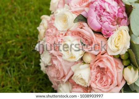 wedding bouquet of pink color from peonies and roses with wedding rings on it